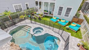 Ein Garten mit Pool, Sitzgelegenheiten im Freien und einem umzäunten Bereich.