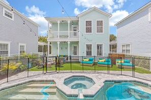 A two-story house with a covered porch, a swimming pool, and outdoor seating.