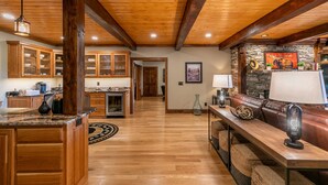 A spacious kitchen with wooden cabinets, a granite countertop, and a stone fireplace. - Haven at Headwaters: Long-range Mountain Views, Pet Friendly, Gameroom (Elk Park)