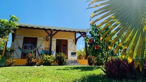 Una casa amarilla con una hamaca y un pequeño porche.