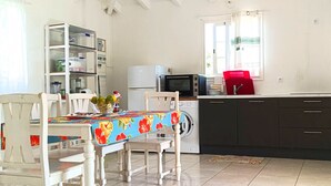 A compact kitchen with a dining area, white cabinets, a microwave, and a washing machine.