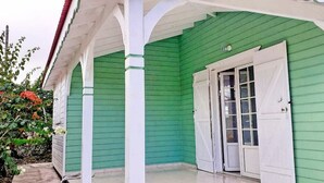 A green building with a white porch and a door.