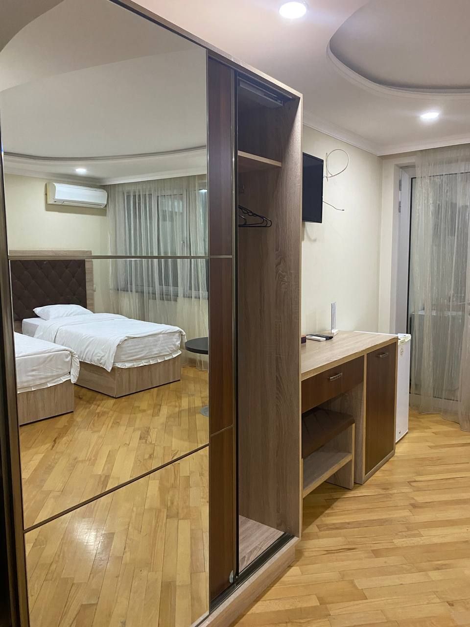Une chambre d’hôtel équipée d’une armoire à miroir, d’un lit, d’un bureau et d’une chaise.
