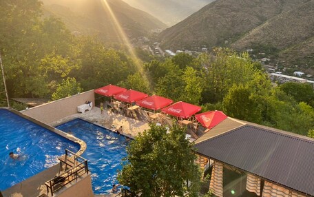 A pool area with red umbrellas, a view of mountains, and a sunset.