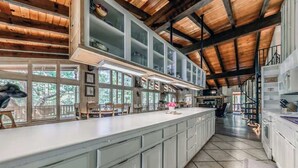 A spacious kitchen with a large island, wooden beams, and a view of the outdoors. - Hidden Buffalo Lodge | Sleeps 13 w/Kid's Loft! (Alto)
