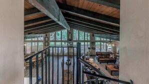 A spacious loft-style room with a high ceiling, large windows, and a staircase leading to an upper level. - Hidden Buffalo Lodge | Sleeps 13 w/Kid's Loft! (Alto)
