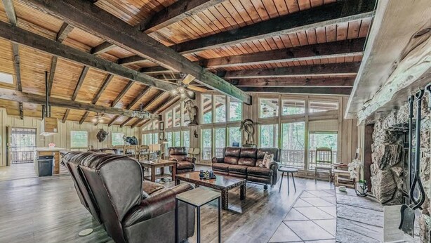A spacious living room with leather sofas, a coffee table, and a stone fireplace. - Hidden Buffalo Lodge | Sleeps 13 w/Kid's Loft! (Alto)