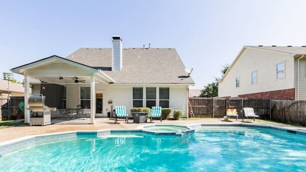 Ein Garten mit Schwimmbad, überdachter Terrasse und einem Haus.