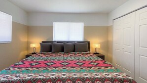 Ein Schlafzimmer mit einem Bett, zwei Nachttischlampen, einem Fenster und einem Kleiderschrank.