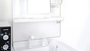 A modern bathroom with a white sink, a mirror, and a built-in heater.