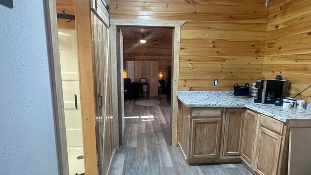 A wooden interior with a kitchen area featuring cabinets, a countertop, and a coffee machine. - Deer Run Cabin (Licking)