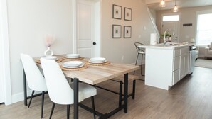 Una cocina moderna con una mesa de comedor de madera, sillas blancas y una isla blanca con un lavaplatos.