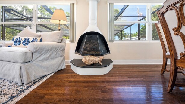 Una sala de estar con chimenea, un sofá, una lámpara y ventanas amplias.