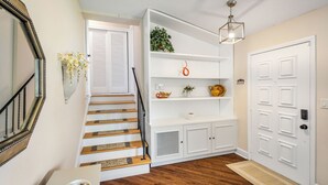 Una escalera con peldaños de madera y barandilla negra, que conduce a una puerta blanca con mirilla.