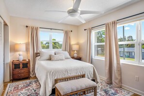 A bedroom with a bed, bedside tables, a bench, a ceiling fan, and large windows with curtains. - 1.5/h theme parks, close to mall,  golf course, 15min to beach, 5min Downtown!  (Melbourne)