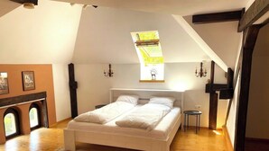 A bedroom with a large bed, a wooden floor, a small table, and a fireplace. - Rose’s OldTown Place - Walkable and Quiet (Brașov)