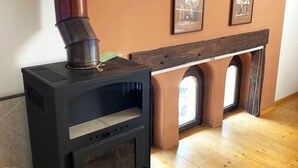 A black wood-burning stove with a chimney, positioned near a fireplace with arched niches. - Rose’s OldTown Place - Walkable and Quiet (Brașov)