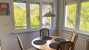 A dining area with a round table, four chairs, and a hanging light fixture. - Rose’s OldTown Place - Walkable and Quiet (Brașov)