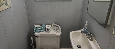 A small bathroom with a toilet, sink, and window with blinds.