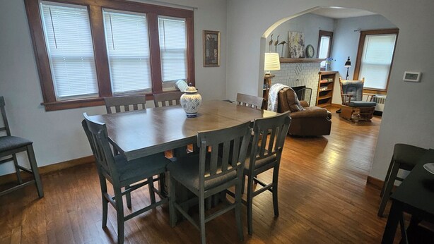 Un comedor con mesa y sillas de madera, un florero y una lámpara de techo original.