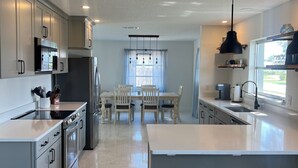 Una cucina moderna con mobili grigi, un'isola centrale e una zona pranzo con tavolo e sedie.