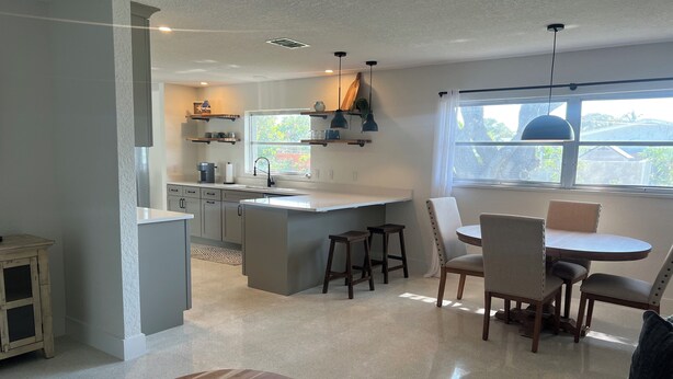 Una cucina moderna con isola centrale, sgabelli da bar e zona pranzo con tavolo rotondo e sedie.