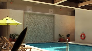 Une piscine intérieure avec un mur carrelé, des plantes en pot, un dispositif de sauvetage et des chaises longues en bois.