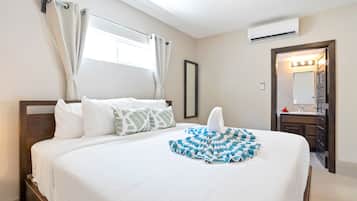 A hotel room with a large bed, a bathroom with a mirror and sink, and a window with curtains.