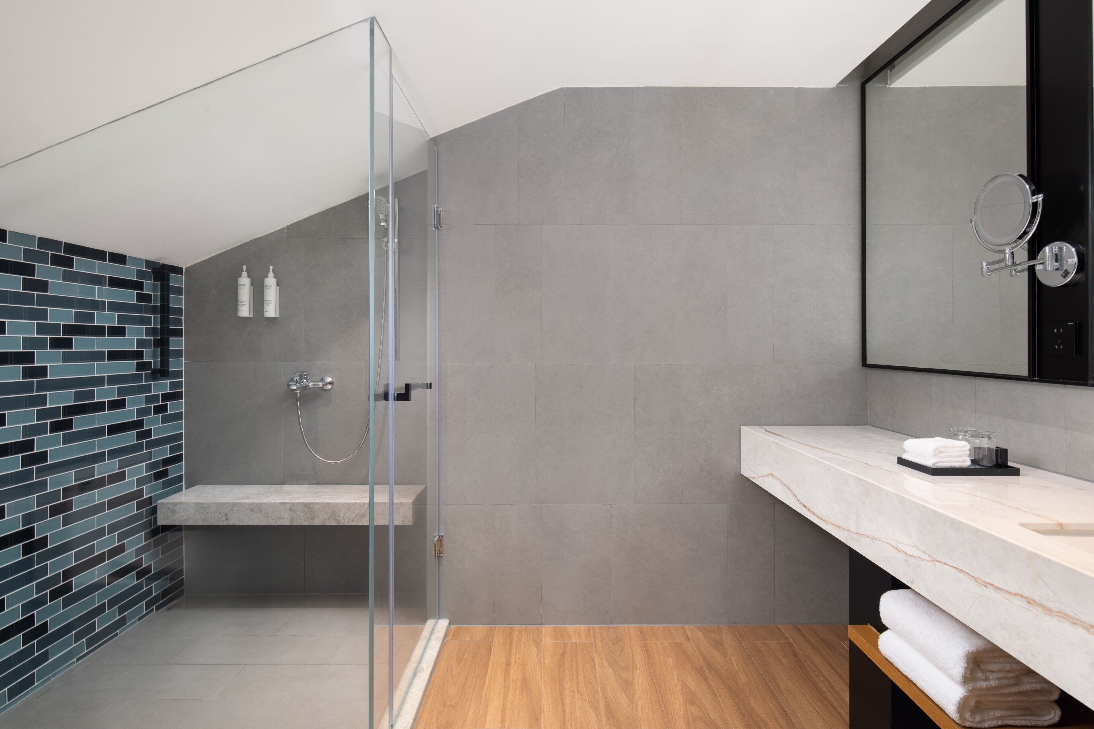 A modern bathroom with a glass shower enclosure, a marble vanity, and a tiled shower area.