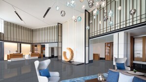 Un vestíbulo amplio con una mesa de recepción, zona de estar y una escultura única.