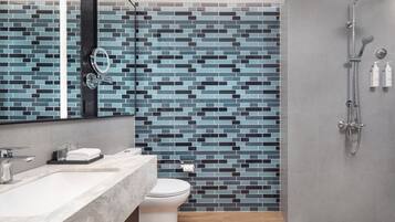 A modern bathroom with a tiled backsplash, a toilet, a sink with a mirror, and a shower area.