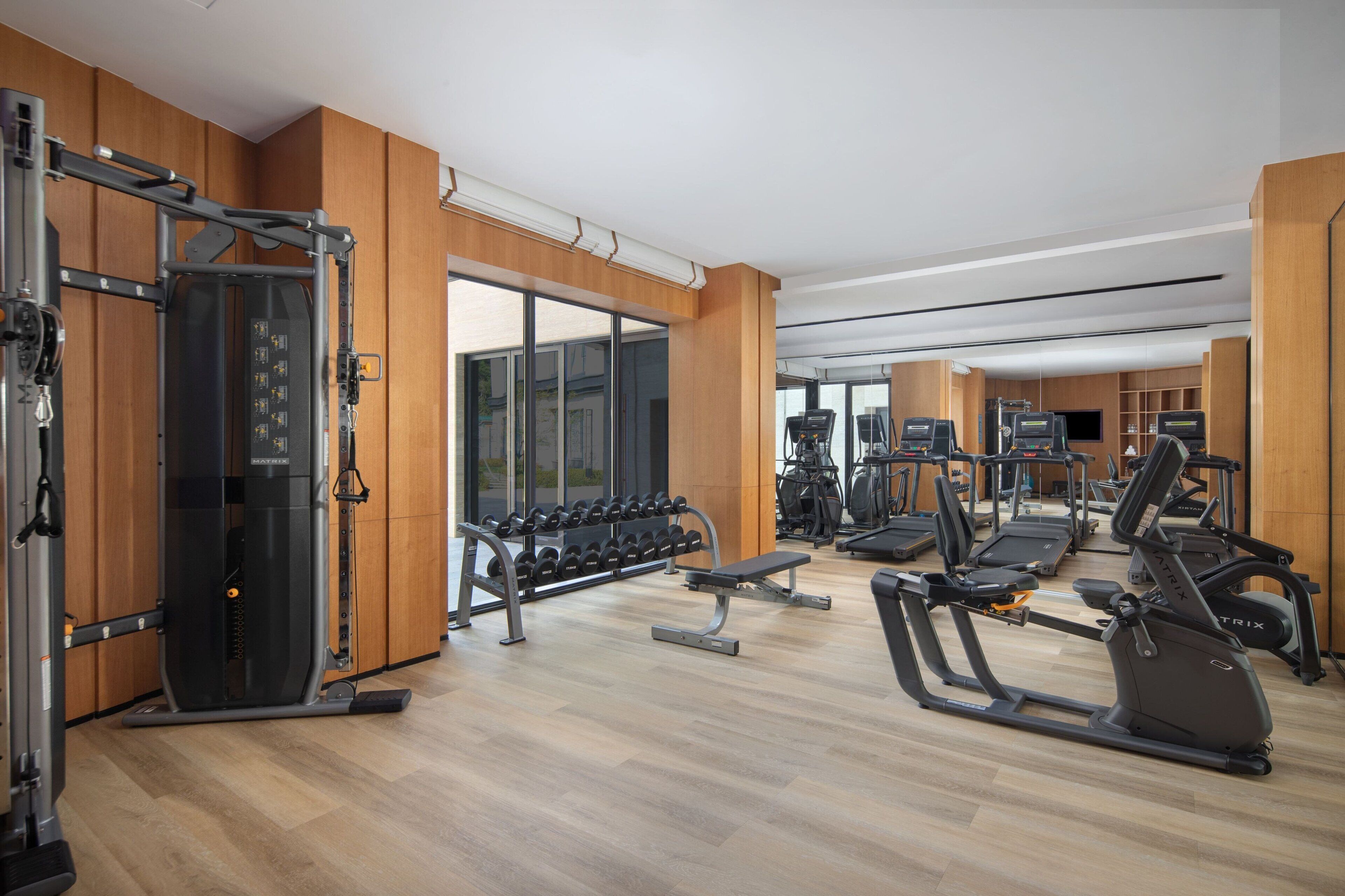 A gym with various exercise equipment, including treadmills, elliptical machines, and free weights.