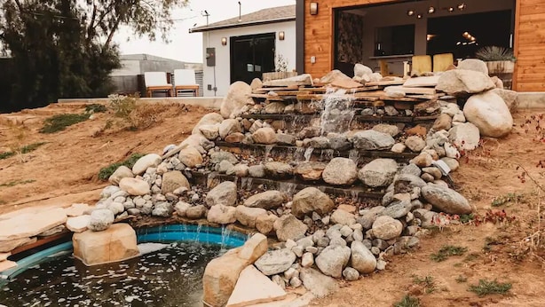 Un edificio moderno con una cascata di pietra e una piscina.