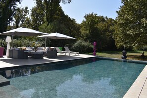 Una piscina con lettini e ombrelloni, immersa nel verde.