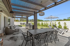 Un patio exterior con una parrilla, asientos y vista al océano.
