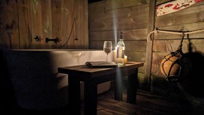 A dimly lit room with a wooden table, a candle, and a wine glass.