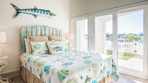 Un dormitorio con una cama grande, cabecera de madera y vistas al exterior a través de un ventanal corredero.