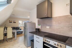 Une cuisine moderne équipée d’un four encastré, d’une plaque de cuisson et d’un réfrigérateur.