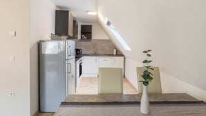 Eine kleine Küche mit Kühlschrank, Spüle und einer Essecke mit Tisch und Stühlen.