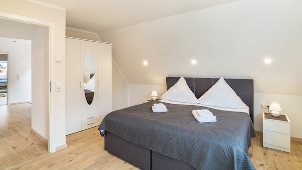 Ein Schlafzimmer mit Bett, Nachttischen, einem Kleiderschrank und einem Spiegel.