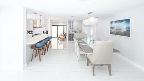 Una cucina moderna con mobili bianchi, un piano di lavoro lungo e luci a sospensione.