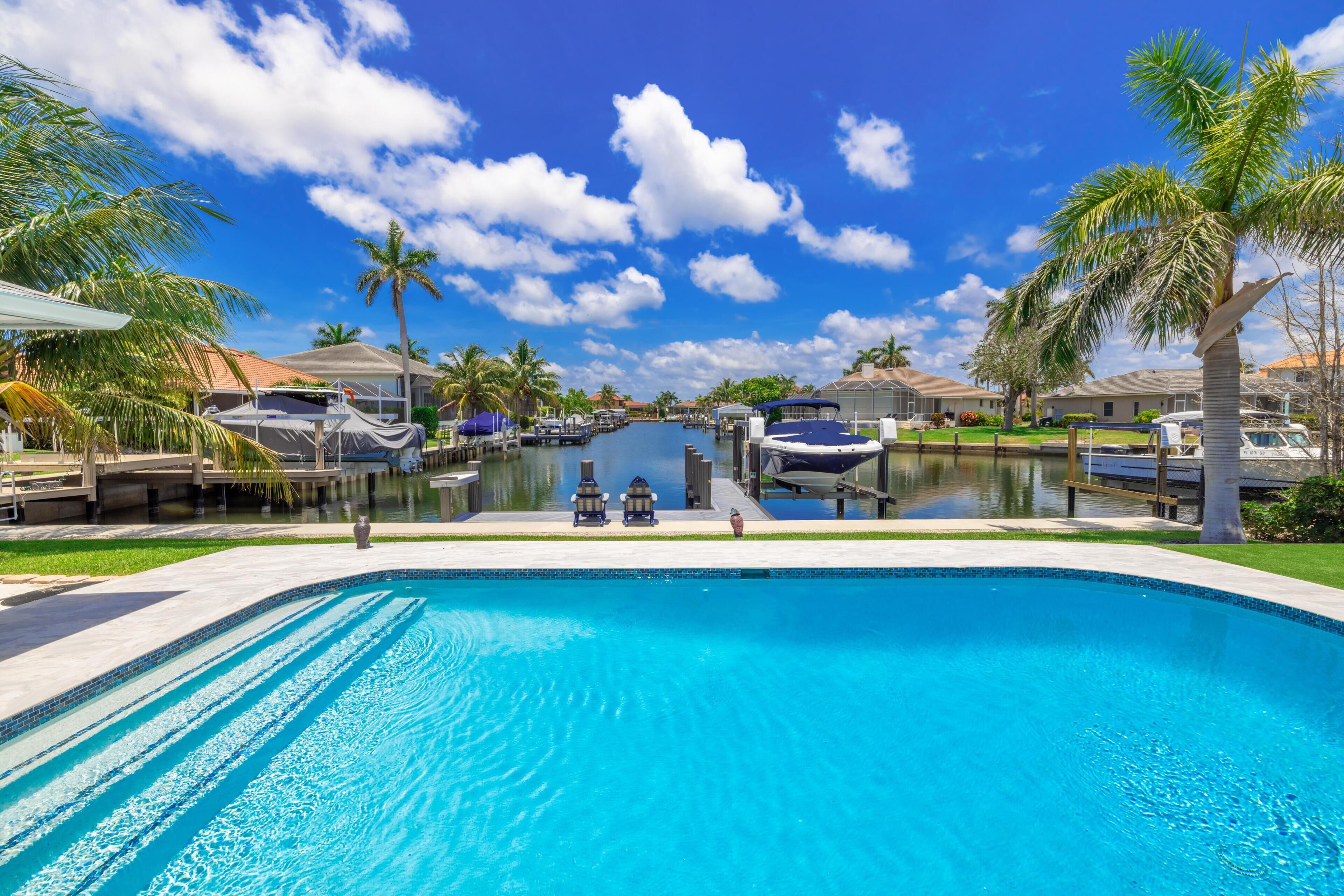 A swimming pool with a view of a marina and houses in the background.