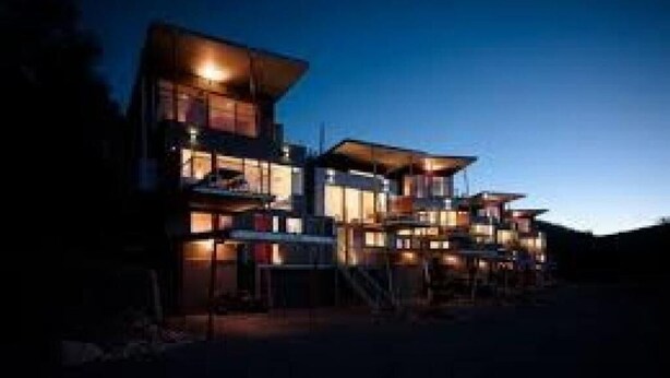 A multi-story building with a modern architectural design, featuring balconies and large windows.