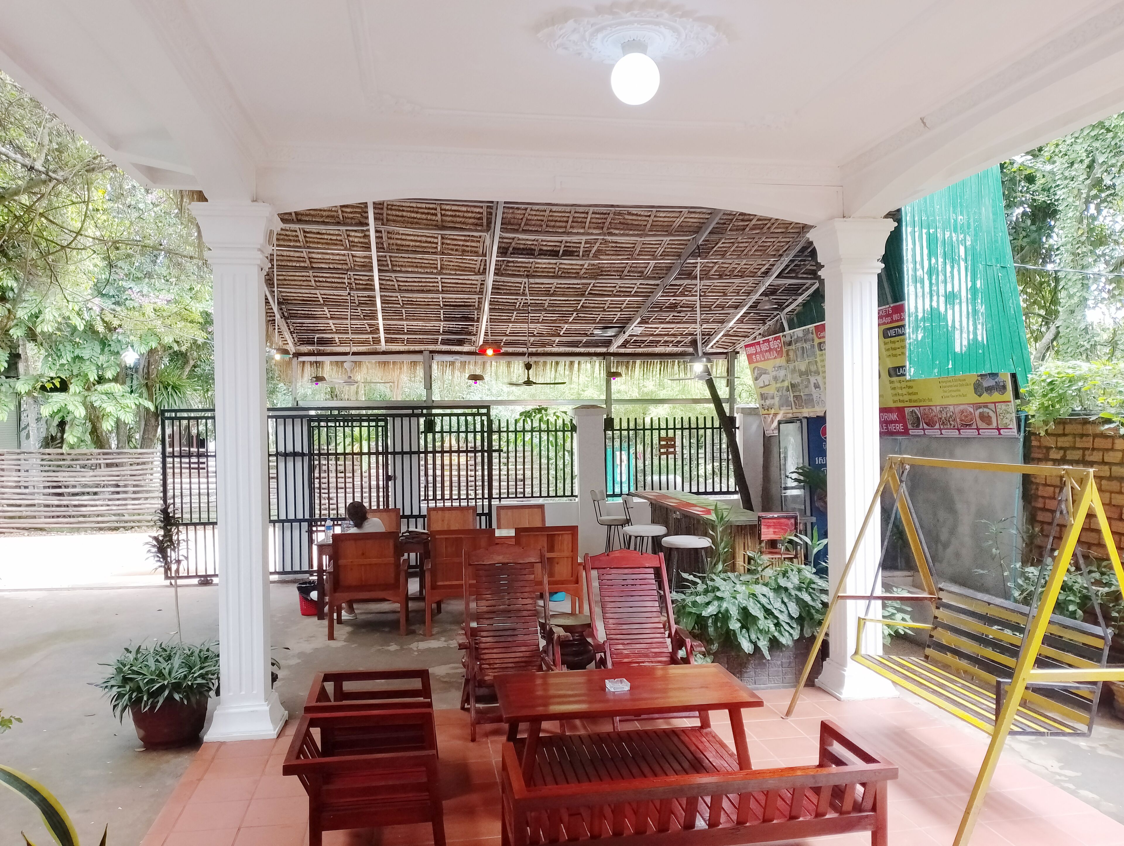 An outdoor seating area with wooden furniture and a thatched roof.