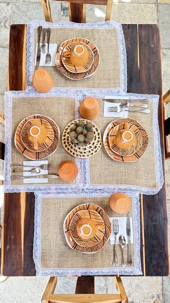 A dining table set with four plates, each with a central design, surrounded by forks, knives, and spoons.