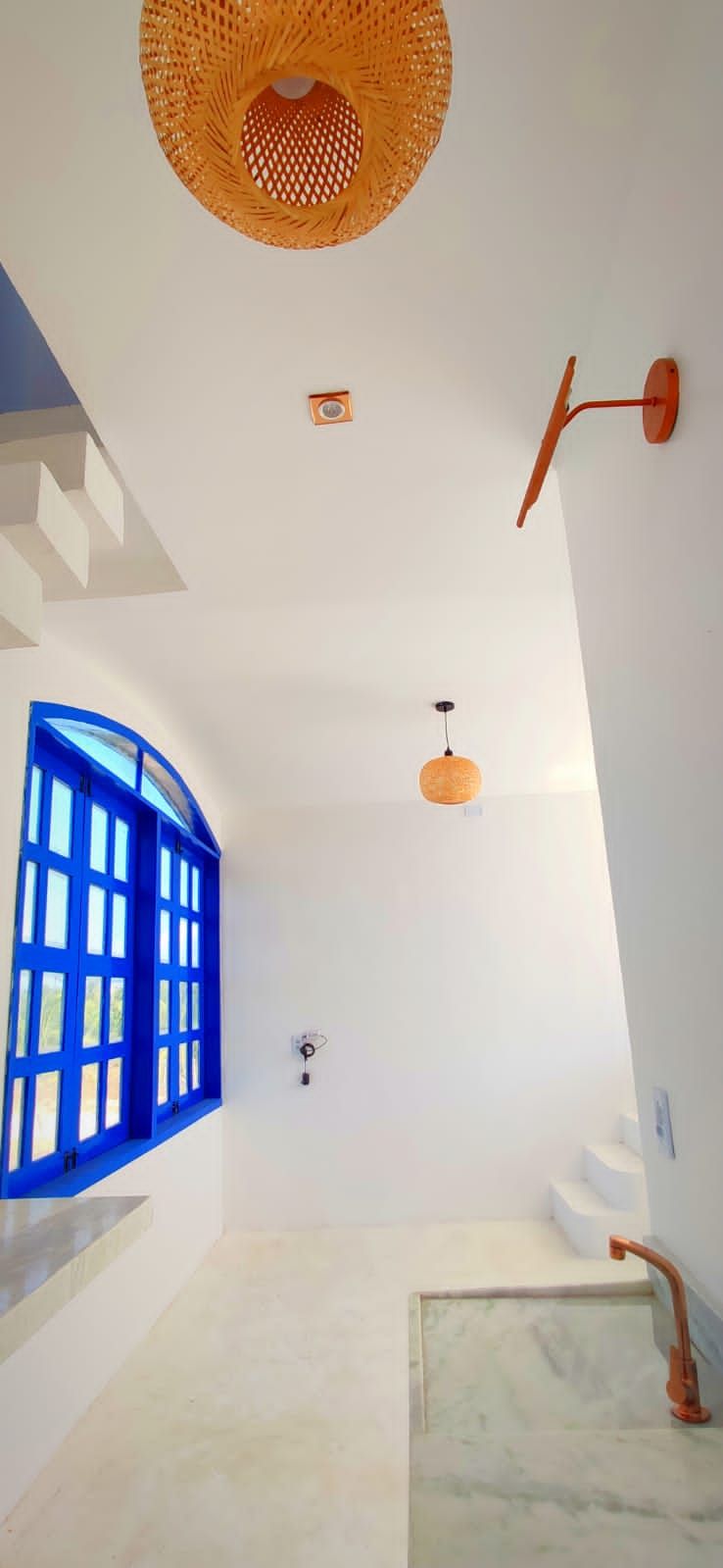 A bathroom with a white sink, a blue window, and a hanging light fixture.