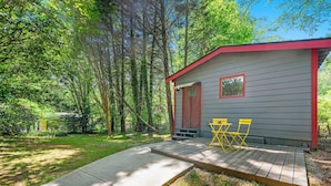 Une petite cabane avec une terrasse et deux chaises jaunes.