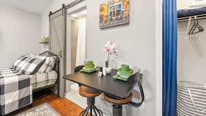 Une chambre à coucher avec un lit, une table à manger avec des chaises, un tableau accroché au mur et une porte coulissante.