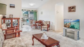 A living room with a wooden coffee table, a television, and a dining area with chairs and a table.