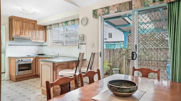 A kitchen with wooden cabinets, a stove, and a dining area with a table and chairs.